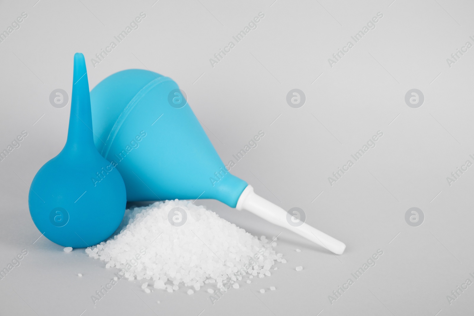 Photo of Enemas and heap of salt on grey background, space for text. Medical treatment