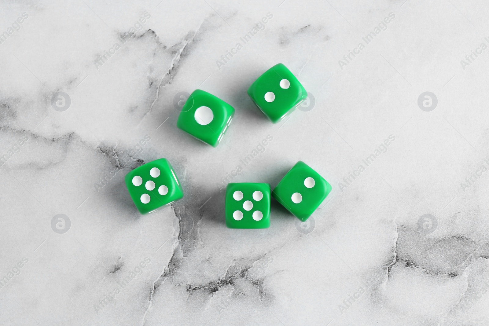 Photo of Many green game dices on white marble table, flat lay