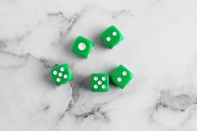 Many green game dices on white marble table, flat lay