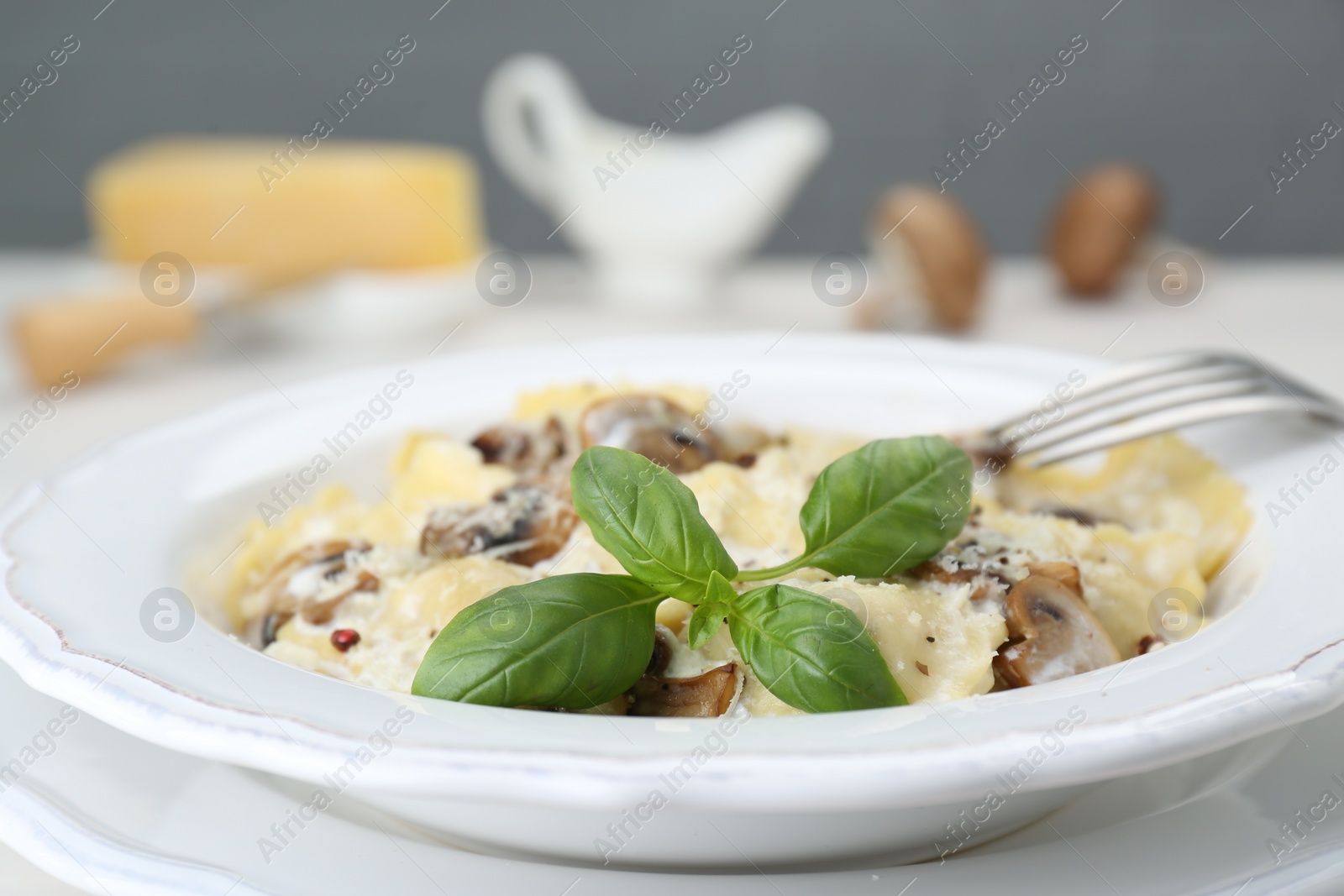 Photo of Delicious ravioli with mushrooms and cheese served on table, closeup