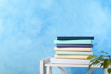 Photo of Stack of books on shelf against color background. Space for text