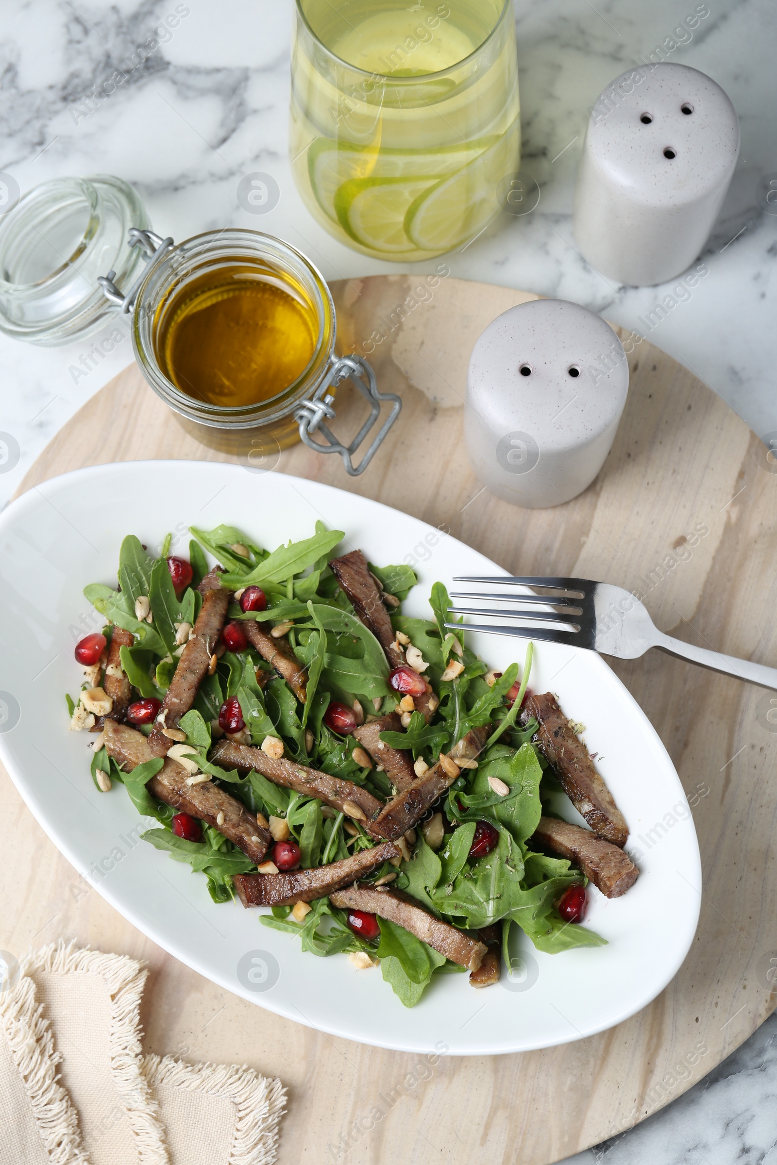 Photo of Delicious salad with beef tongue, arugula, seeds and fork served on white marble table, flat lay