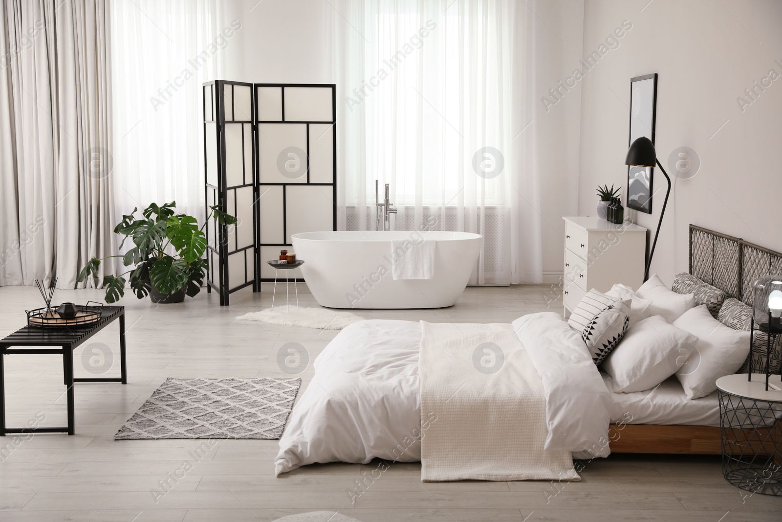 Photo of Stylish light apartment interior with white bathtub and bed