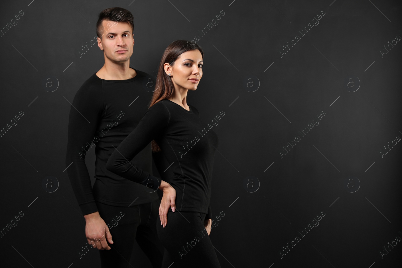 Photo of Couple wearing thermal underwear on black background. Space for text