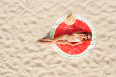 Woman sunbathing on round beach towel at sandy coast, aerial view