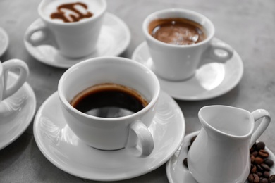 Photo of Cups of fresh aromatic coffee on grey background