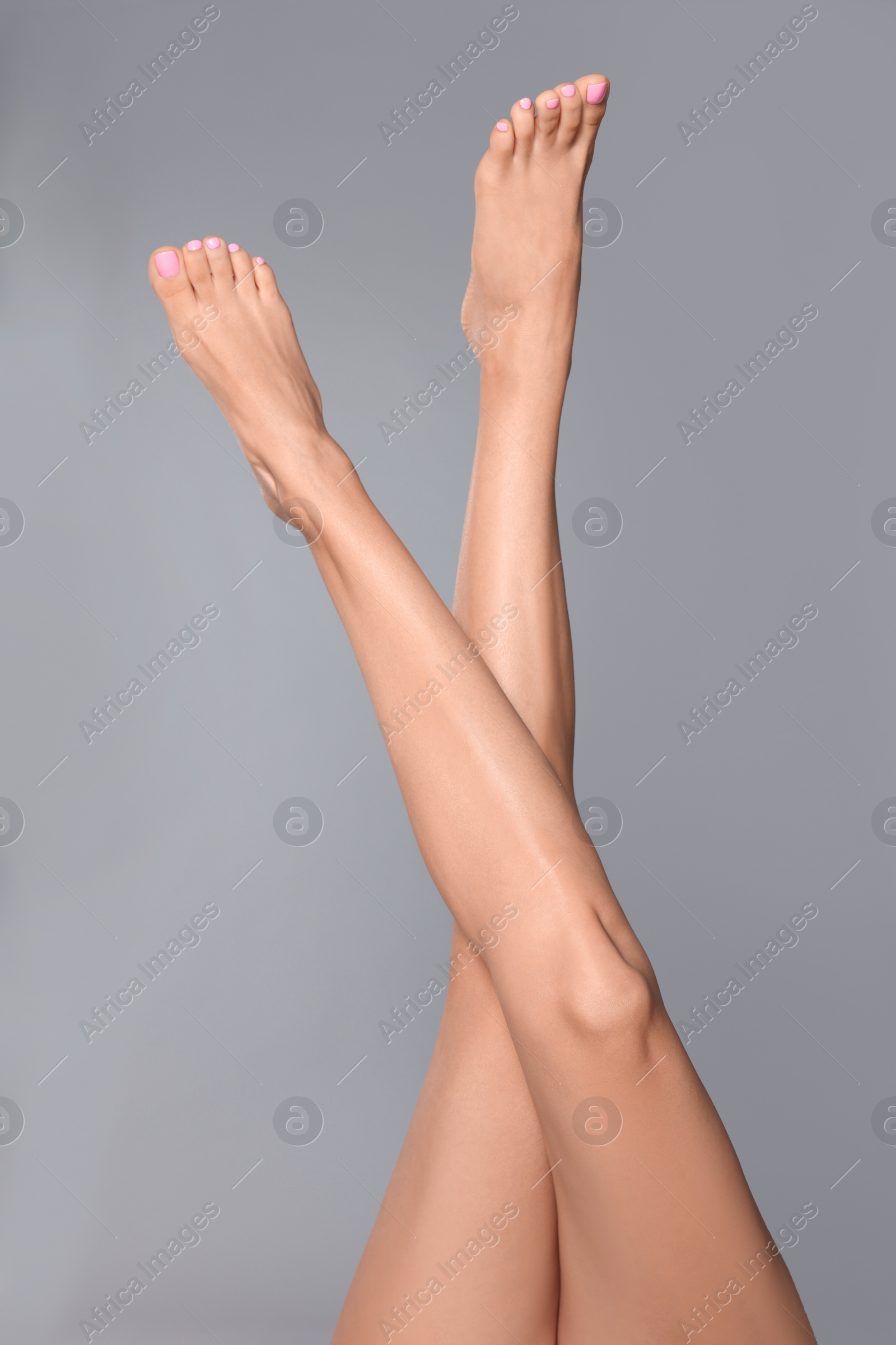 Photo of Woman with beautiful long legs on grey background, closeup