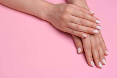 Photo of Woman showing her manicured hands with white nail polish on pink background, closeup. Space for text