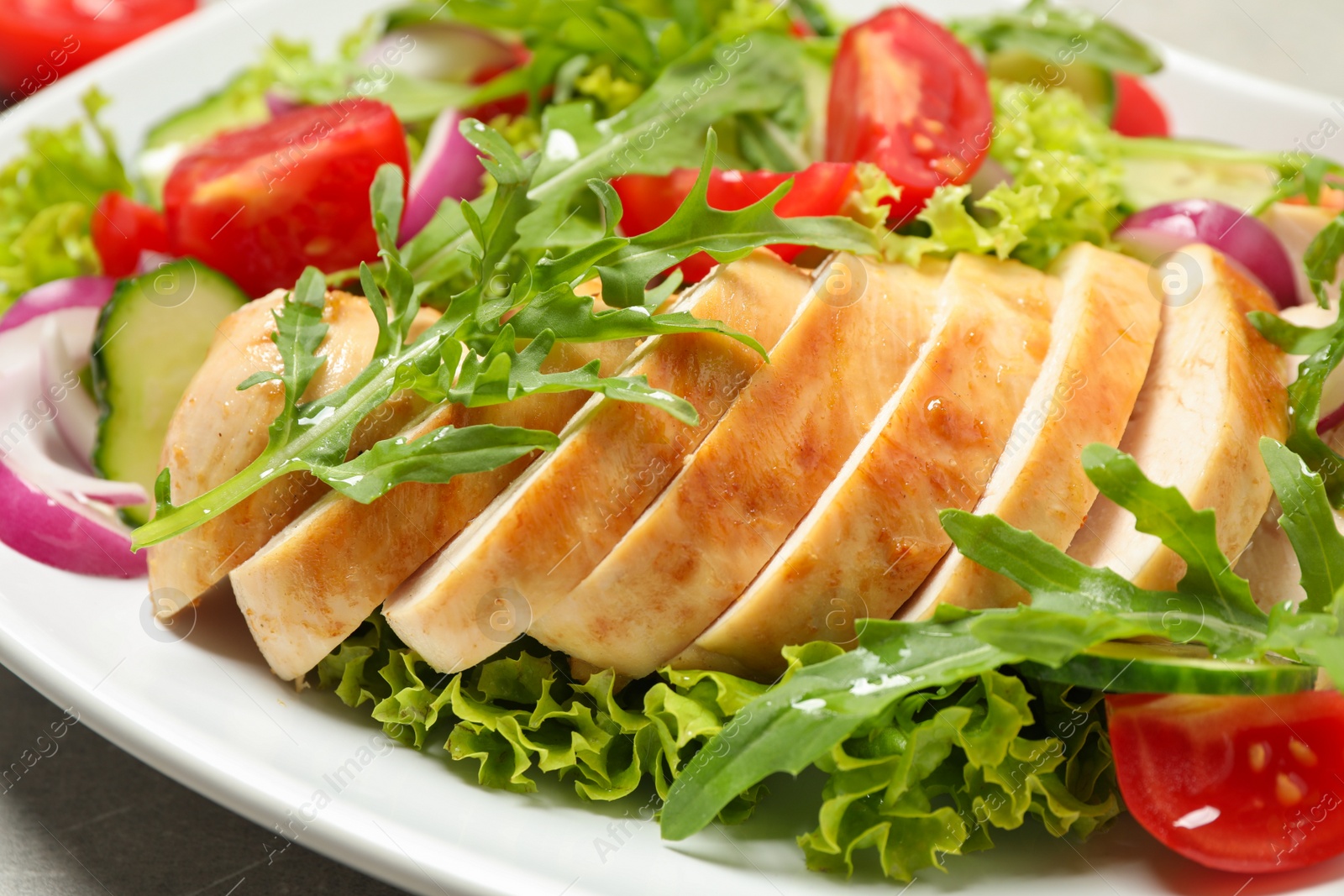 Photo of Delicious salad with meat, arugula and vegetables on plate, closeup