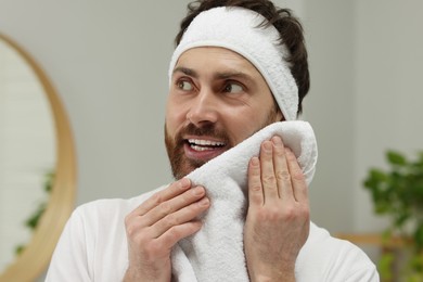 Photo of Washing face. Man with headband and towel in bathroom