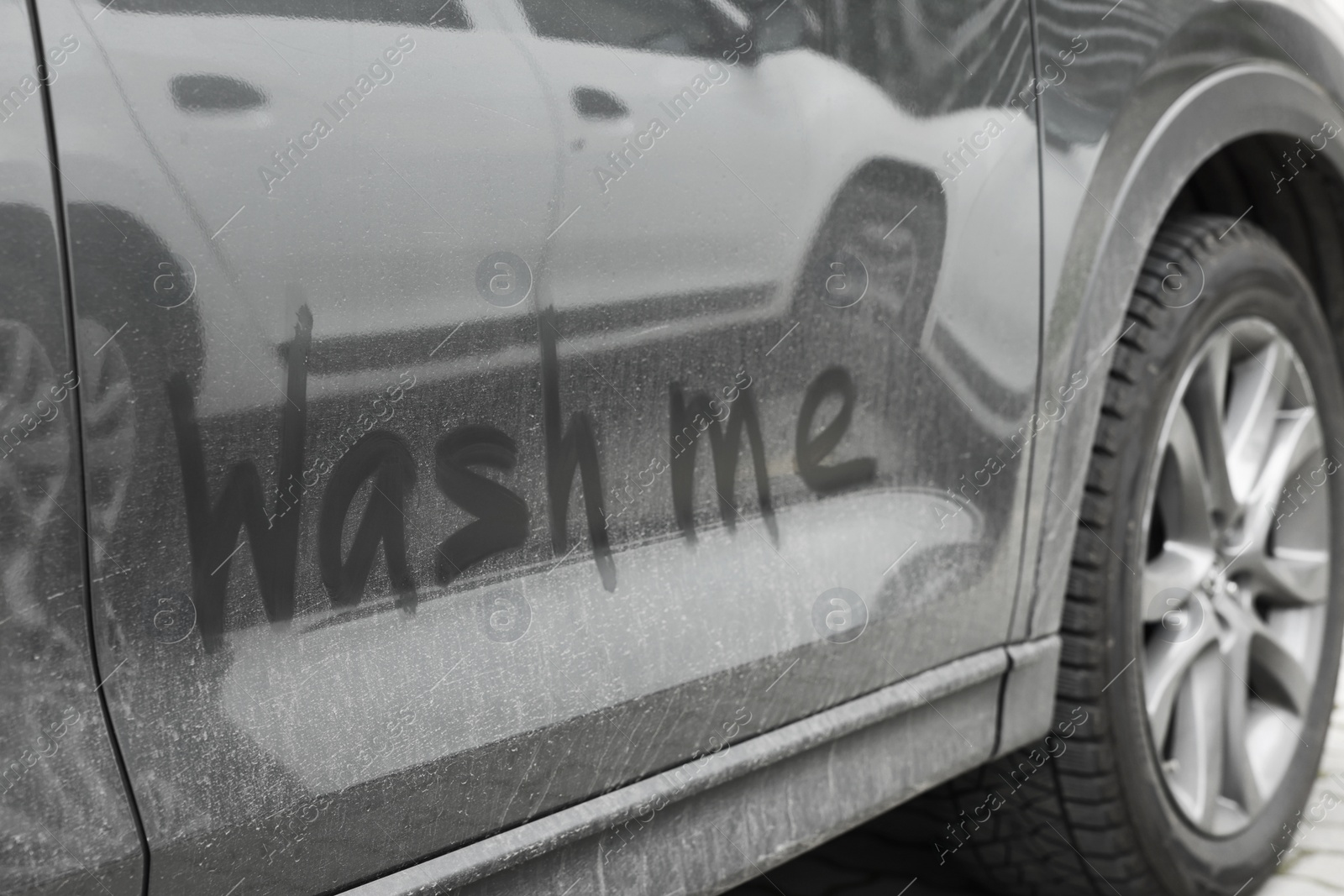 Photo of Phrase Wash Me written on dirty car, closeup