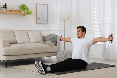 Photo of Overweight man doing exercise with dumbbells on mat at home, space for text