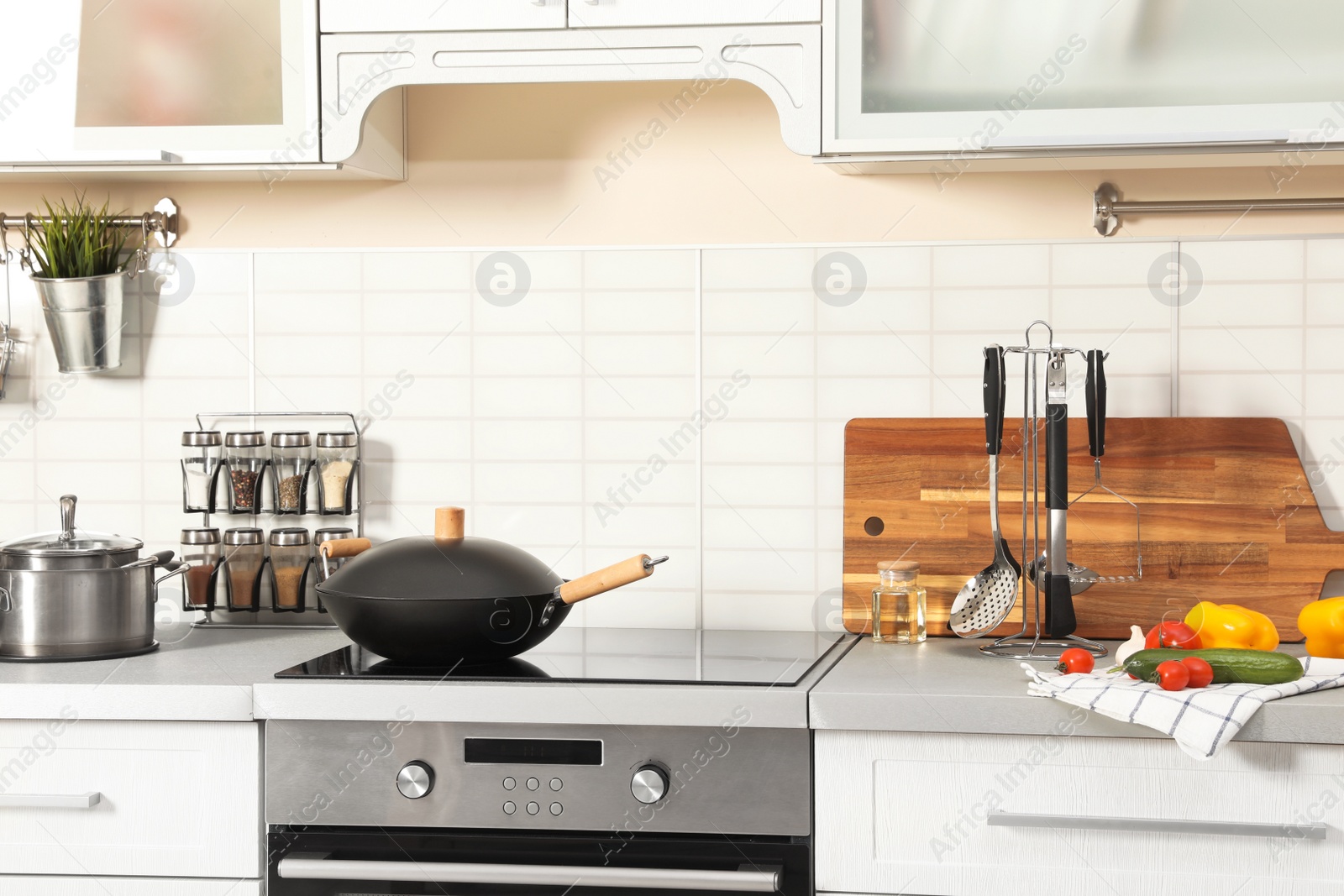 Photo of Set of clean cookware, utensils and products on table in modern kitchen