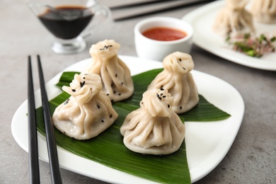 Photo of Plate with tasty baozi dumplings and chopsticks on table