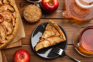 Photo of Delicious apple pie served with tea on wooden table, flat lay