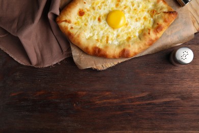 Photo of Fresh homemade khachapuri with cheese and egg on wooden table, flat lay. Space for text