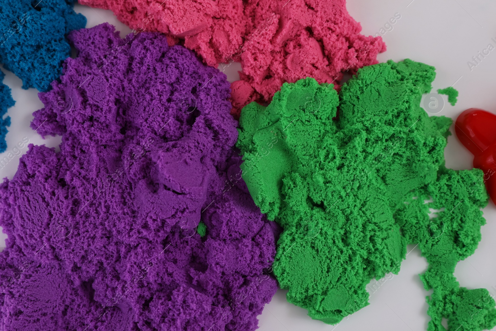 Photo of Colorful kinetic sand on white table, flat lay