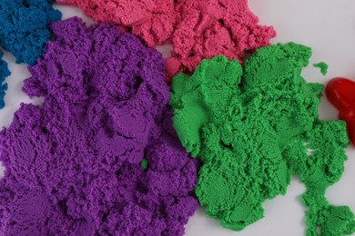 Photo of Colorful kinetic sand on white table, flat lay