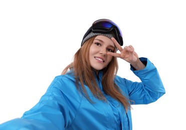 Photo of Beautiful woman in ski goggles taking selfie on white background