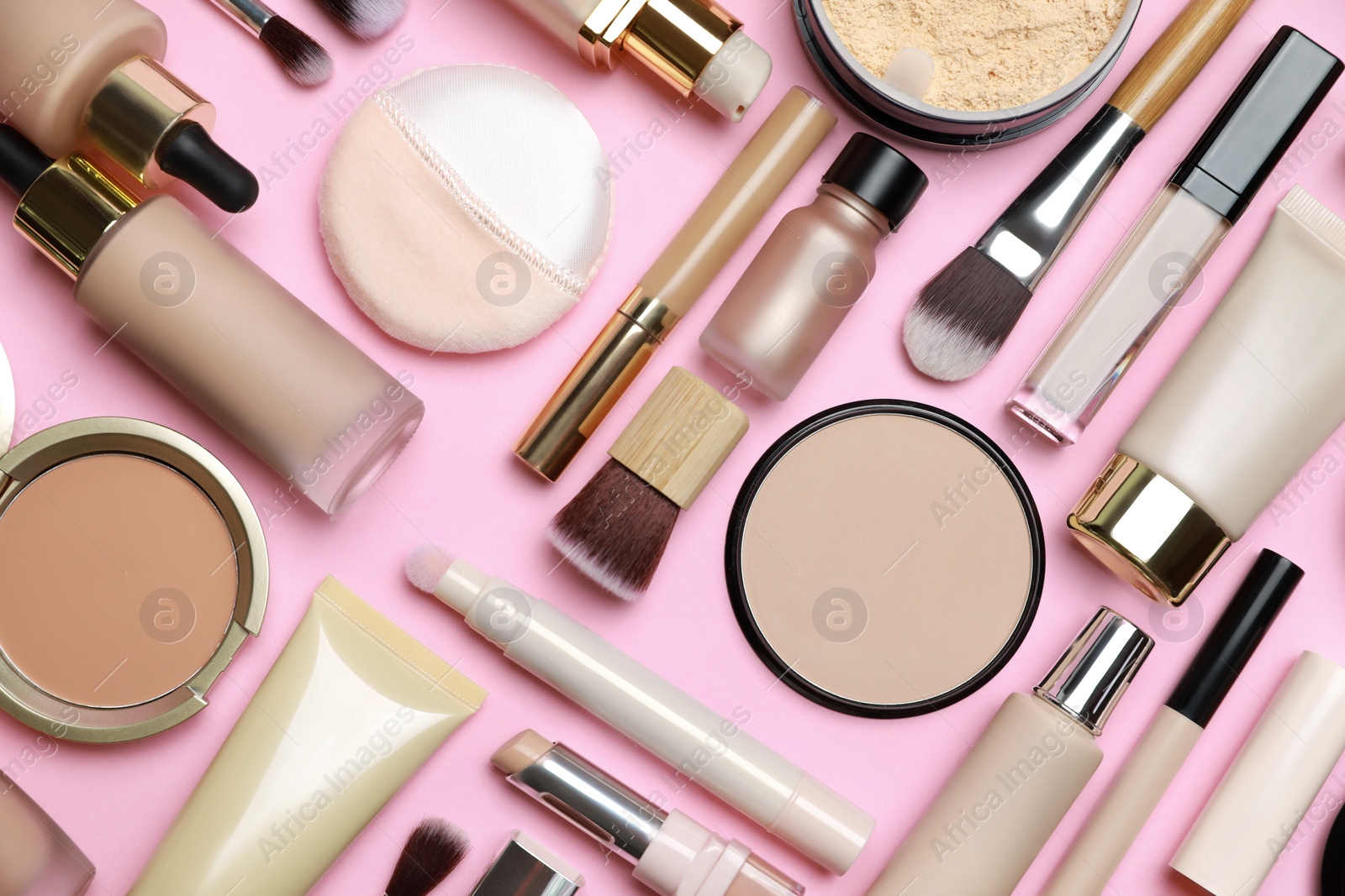 Photo of Face powders and other decorative cosmetic products on pink background, flat lay