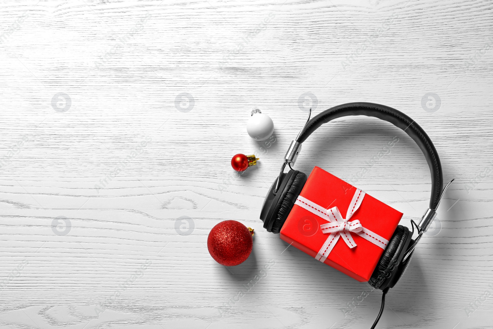 Photo of Flat lay composition with gift box and headphones on wooden background. Christmas music concept