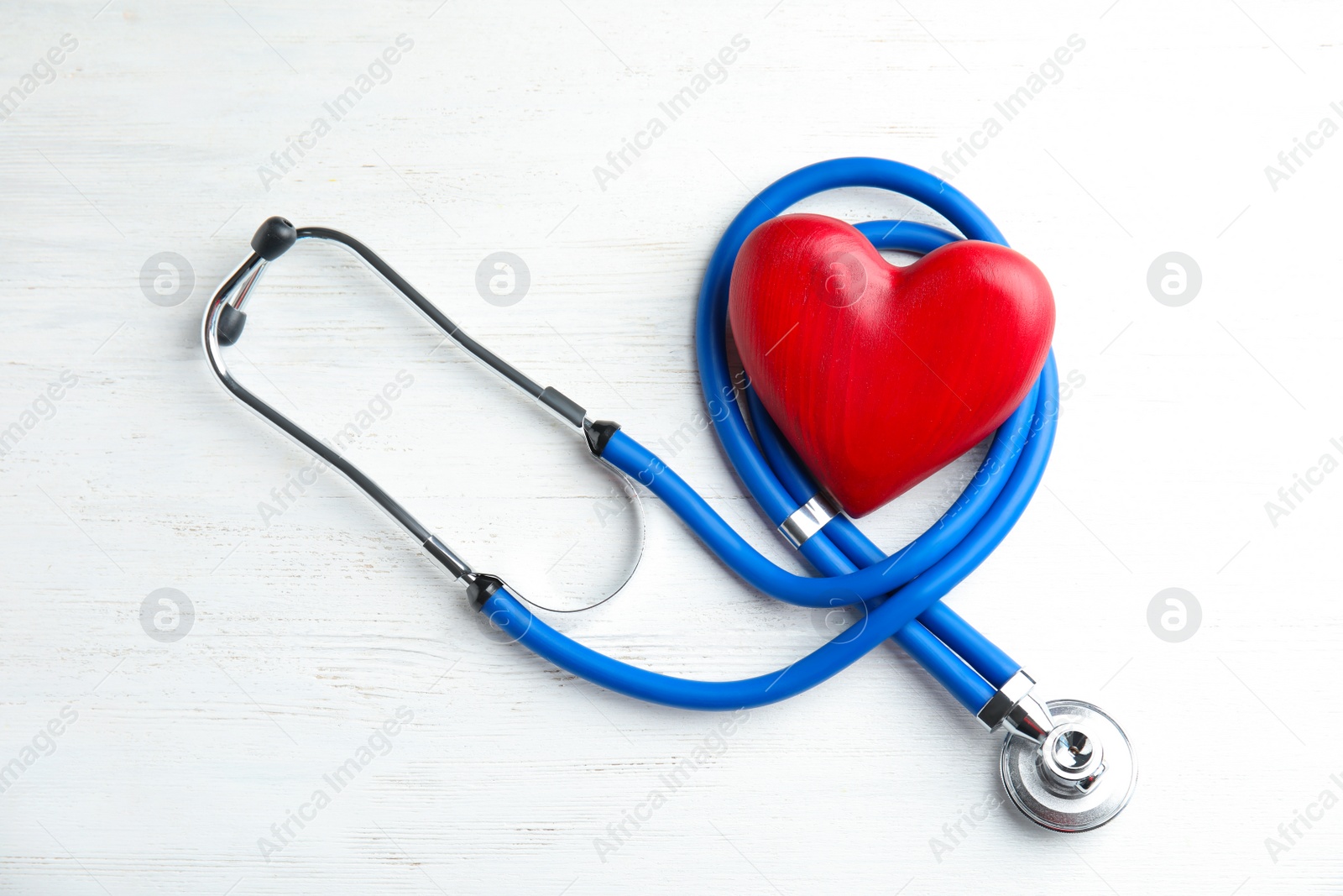 Photo of Stethoscope and red heart on wooden background, top view. Cardiology concept