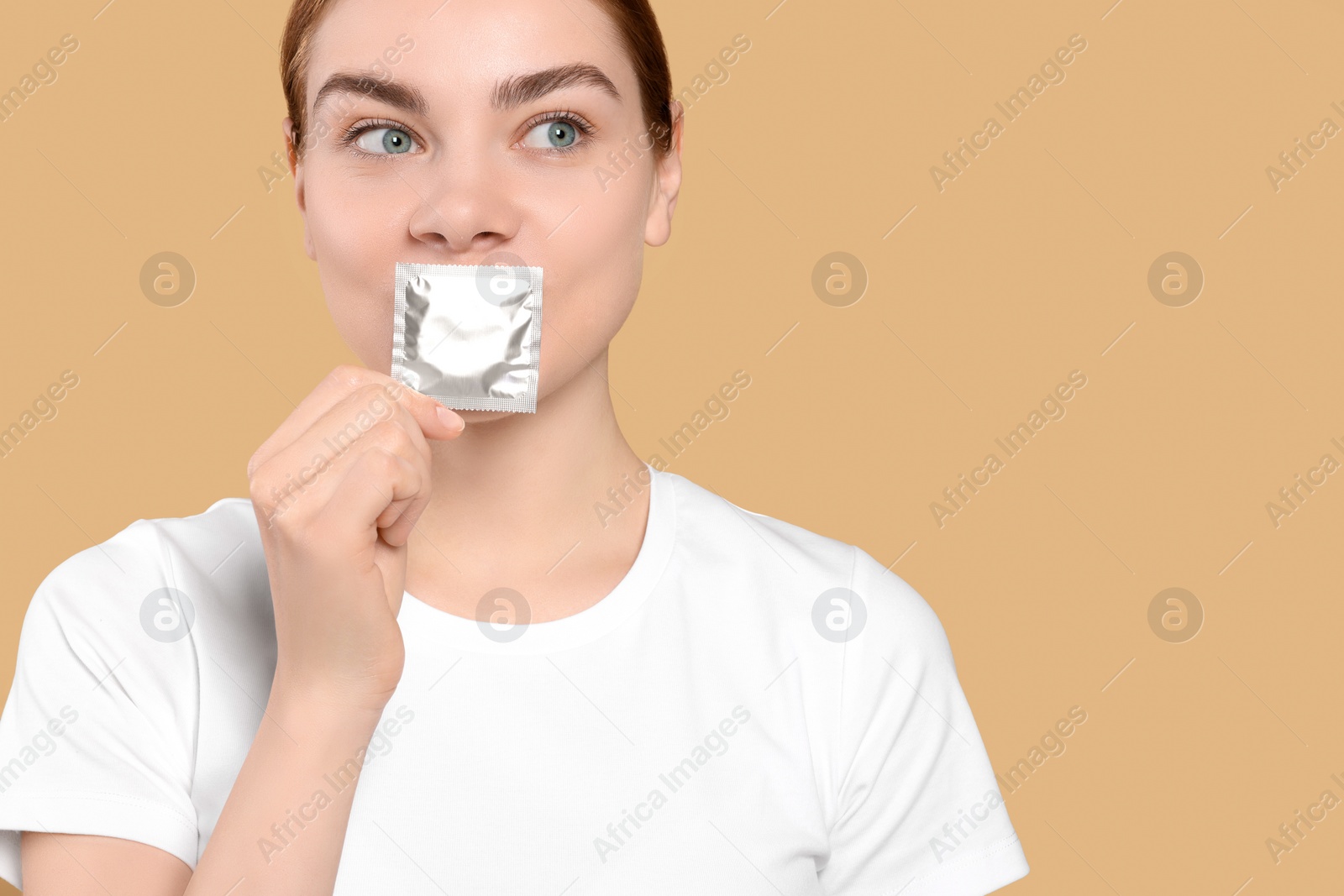 Photo of Woman holding condom on beige background, space for text. Safe sex