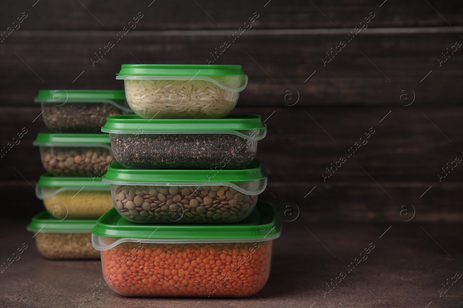 Photo of Plastic containers filled with food products on brown table. Space for text