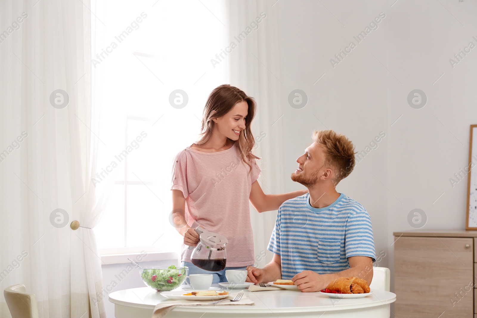 Photo of Happy young couple having breakfast at table in room