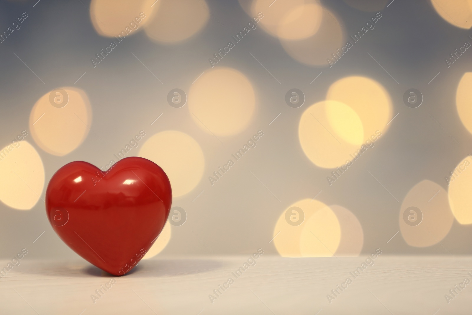 Photo of Heart on table against blurred lights. Space for text