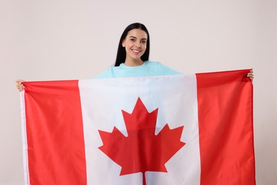 Photo of Happy young woman with flag of Canada on beige background