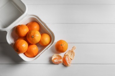 Photo of Paper box with fresh ripe tangerines on white wooden table, flat lay. Space for text