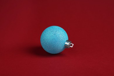 Photo of One light blue Christmas ball on red background