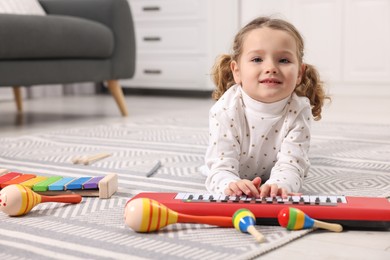 Photo of Little girl playing toy piano at home