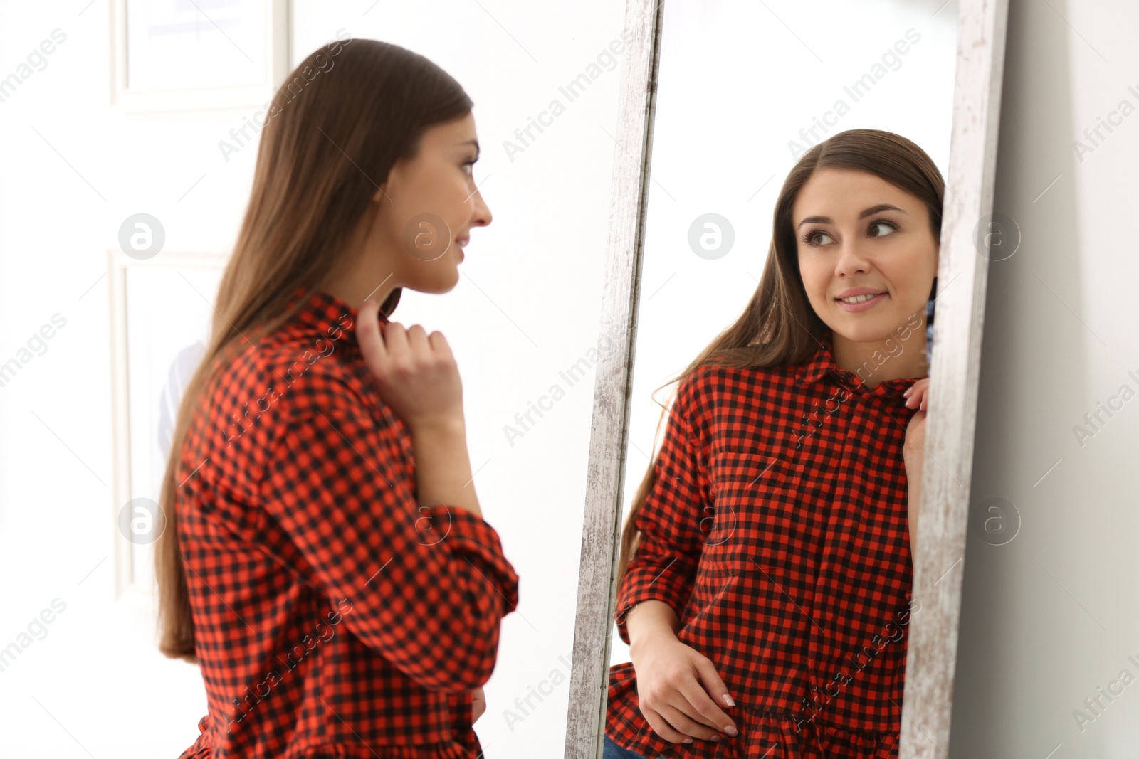 Photo of Young beautiful woman looking in mirror indoors