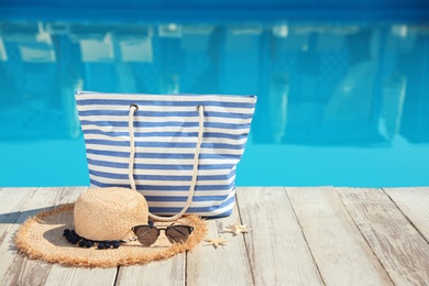 Photo of Beach accessories on wooden deck near outdoor swimming pool, space for text