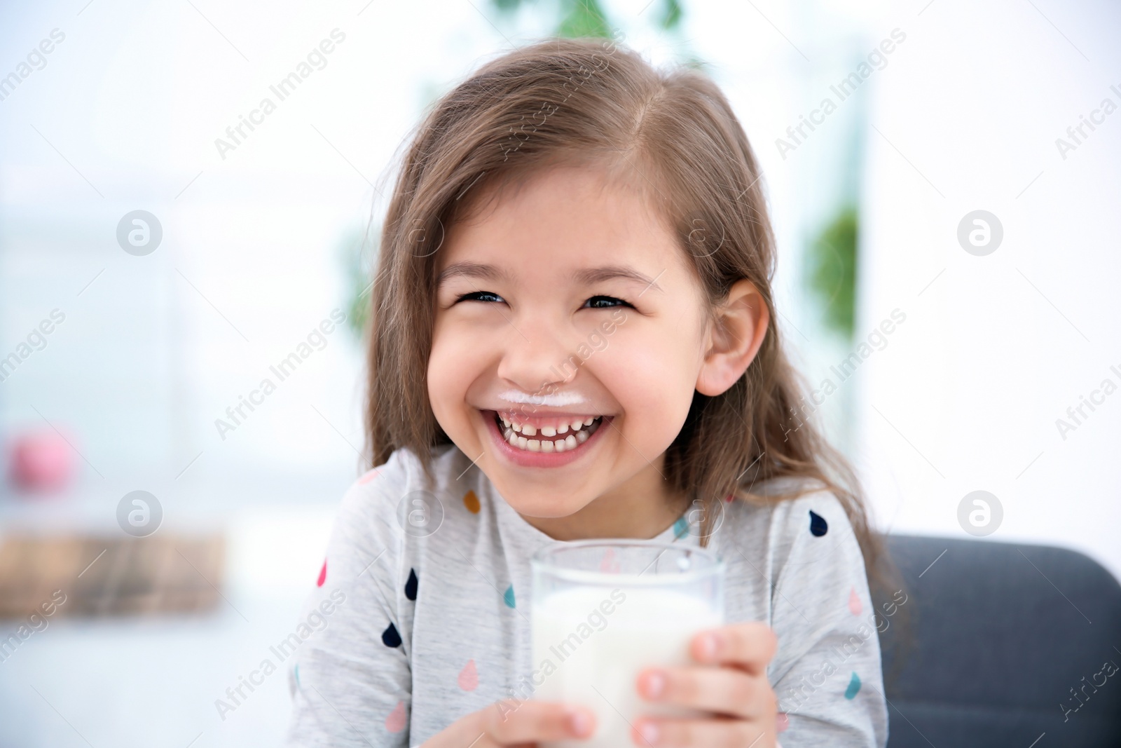 Photo of Cute little girl with glass of milk indoors