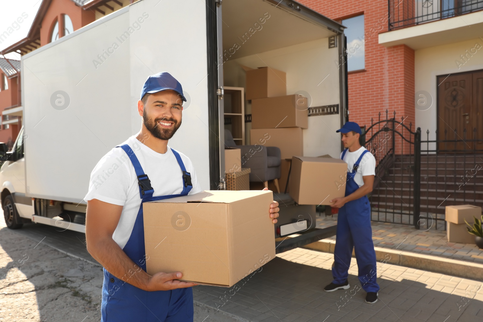 Photo of Workers unloading boxes from van outdoors. Moving service