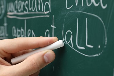 English teacher writing with chalk on green chalkboard, closeup