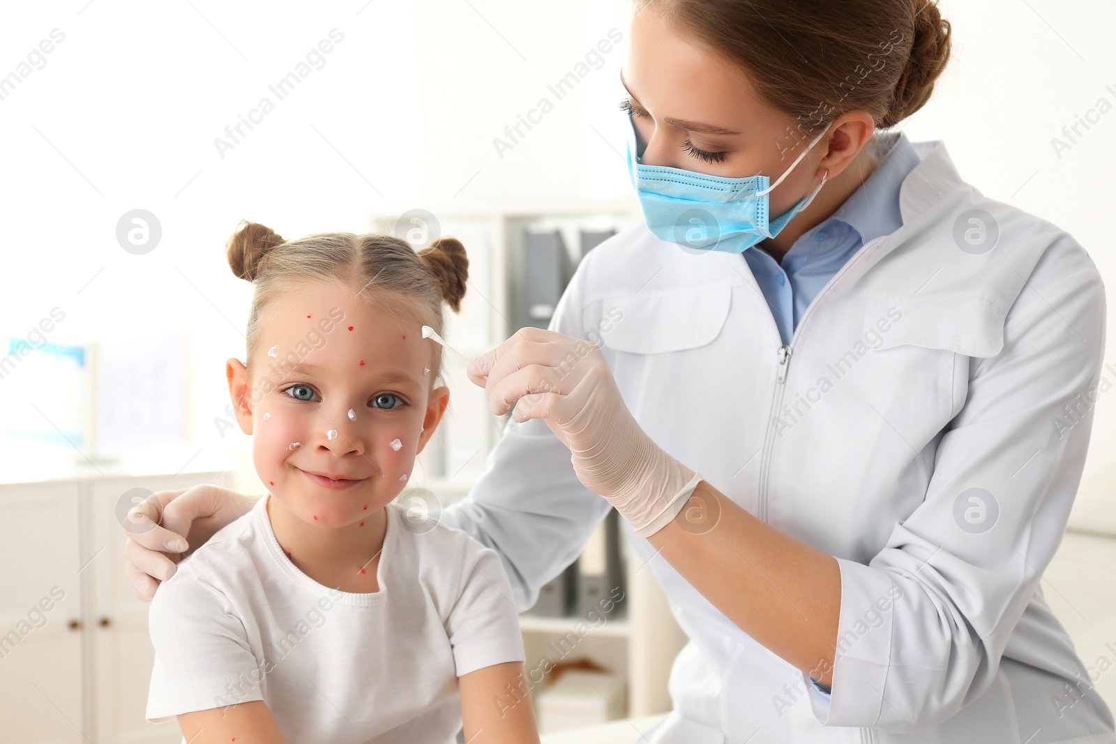 Photo of Doctor applying cream onto skin of little girl with chickenpox in clinic. Varicella zoster virus