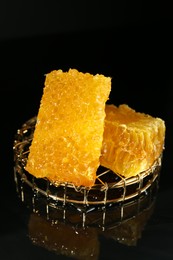 Photo of Natural honeycombs with tasty honey on black background