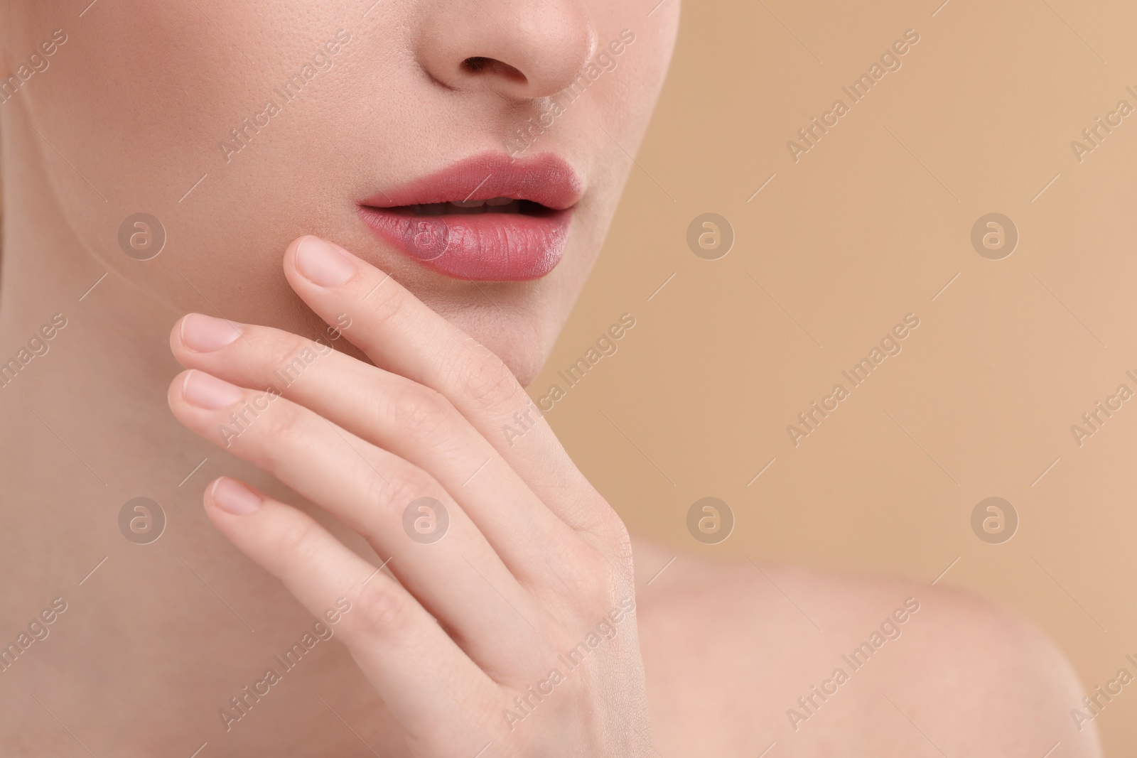 Photo of Young woman with beautiful full lips on beige background, closeup