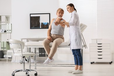 Orthopedist examining patient with injured arm in clinic