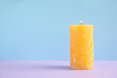 Alight wax candle on color background. Space for text