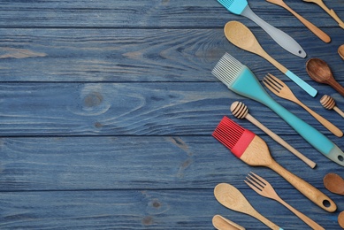 Set of modern cooking utensils on blue wooden table, flat lay. Space for text