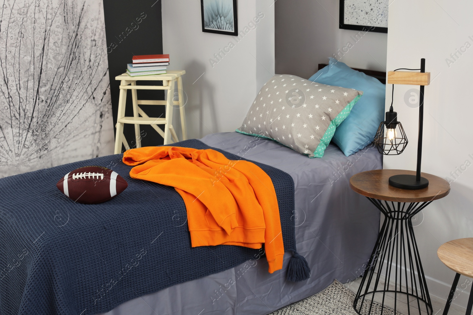 Photo of Stylish teenager's room interior with comfortable bed, lamp and football ball