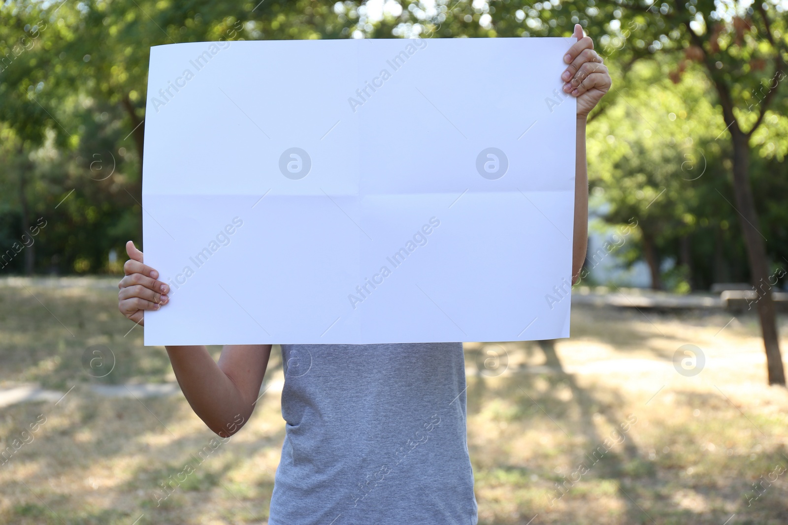 Photo of Woman holding blank poster outdoors. Mockup for design