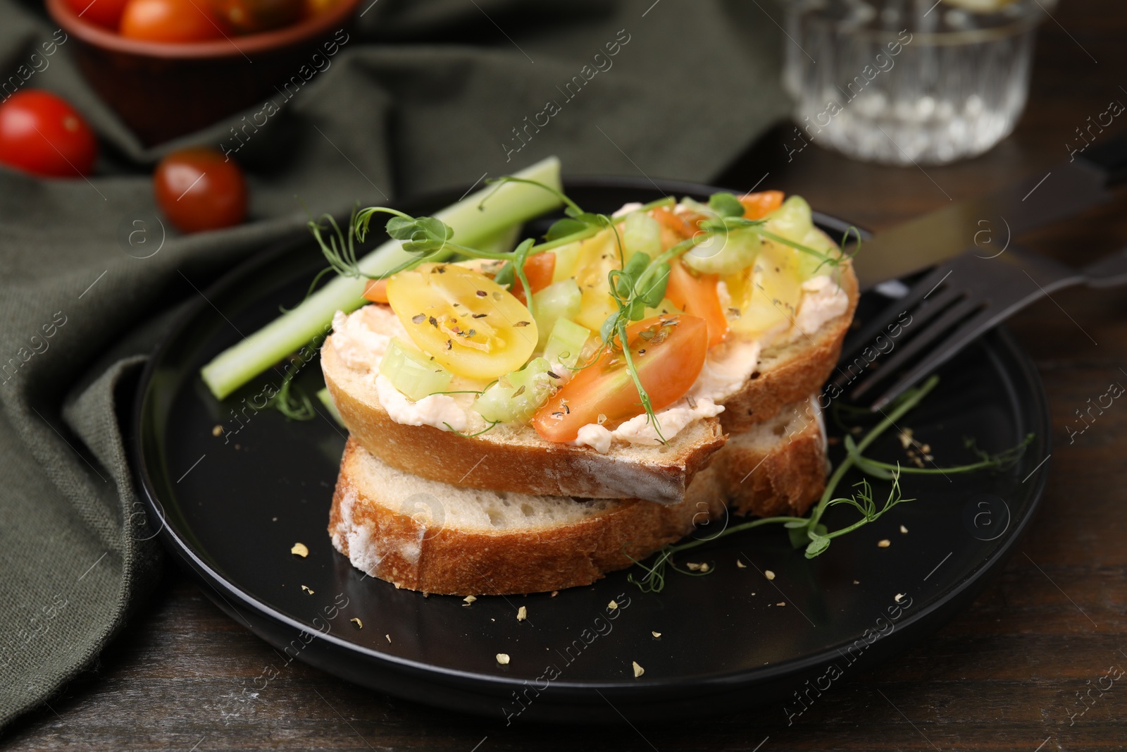 Photo of Tasty vegan sandwich with tomatoes, celery and microgreens on wooden table