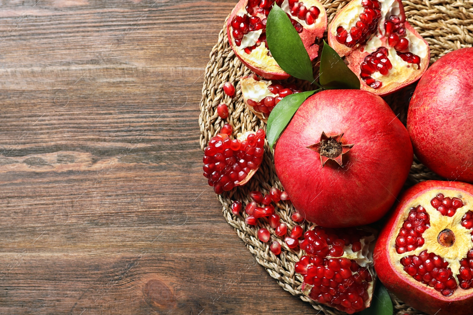 Photo of Composition with ripe pomegranates and space for text on wooden background, top view