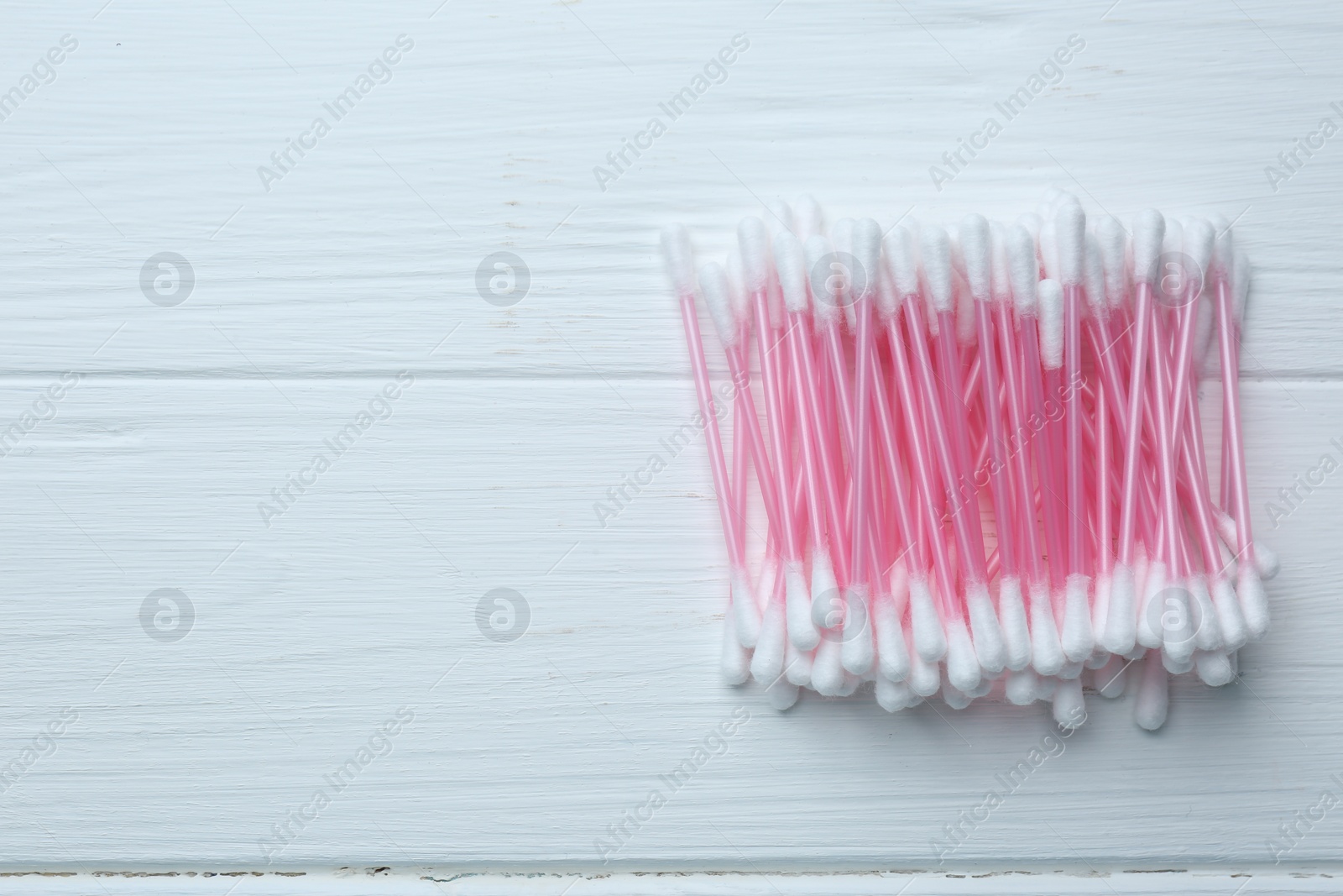 Photo of Many cotton buds on white wooden table, flat lay. Space for text
